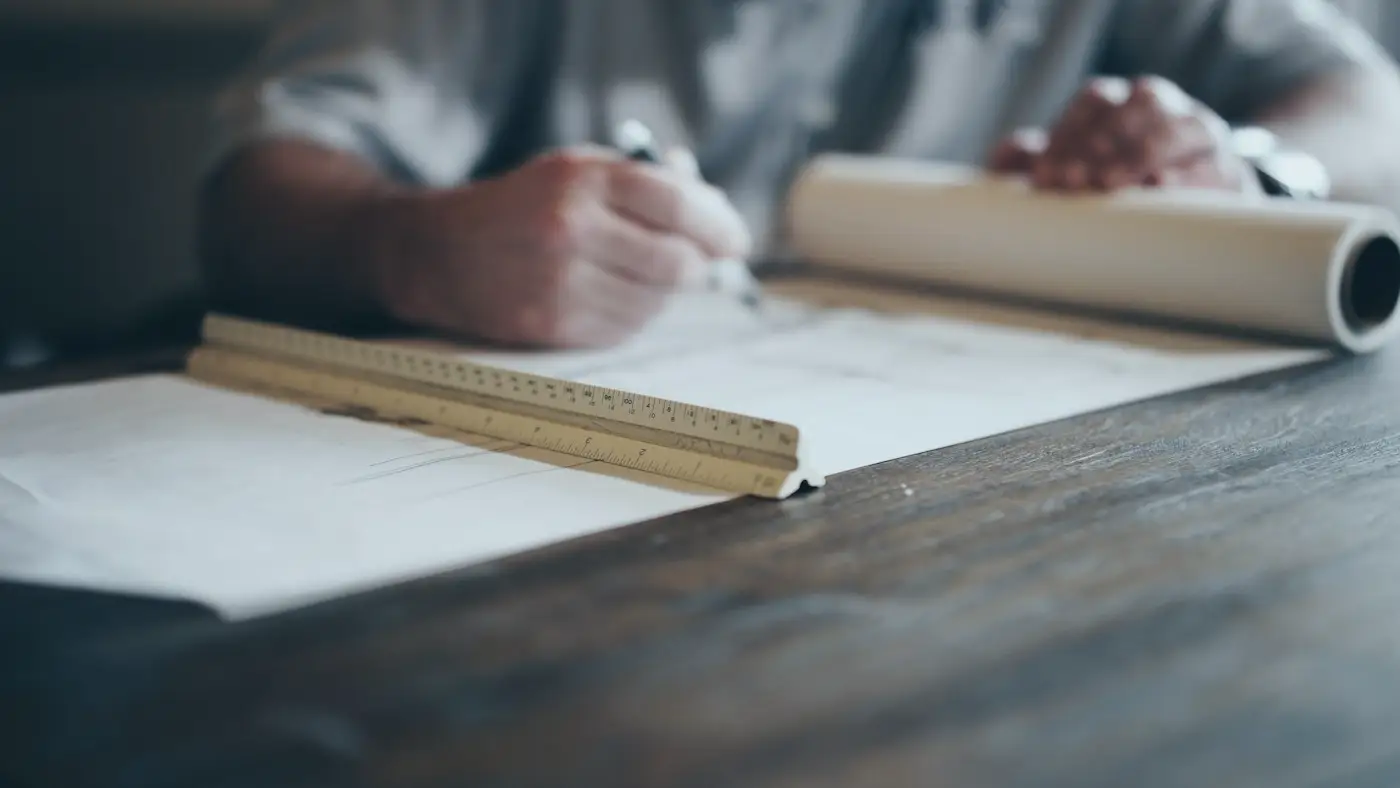 Une main dessine un plan à la règle d'architecte