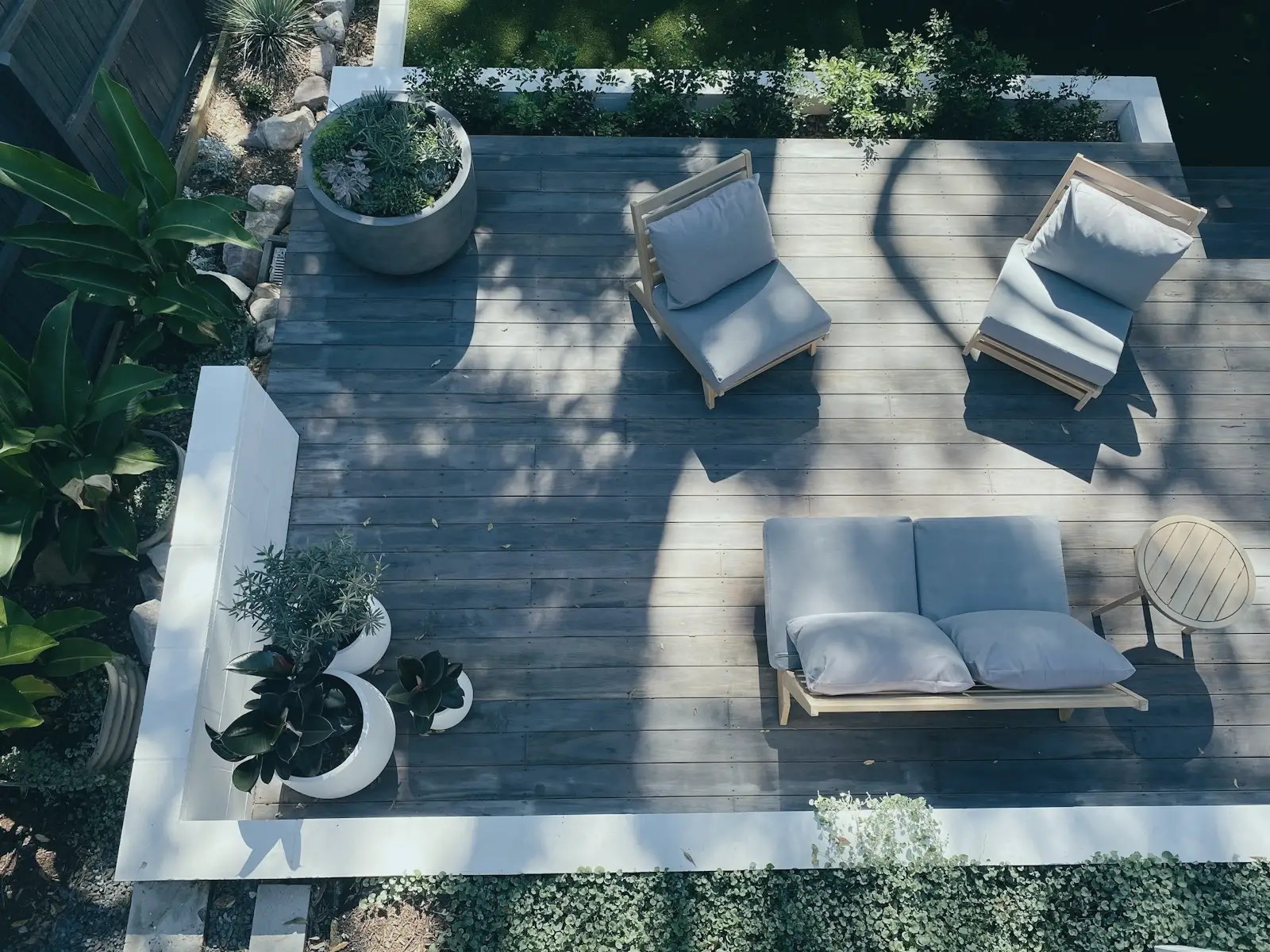 Vue de dessus d'une terrasse en bois avec fauteuils, pots et plantations